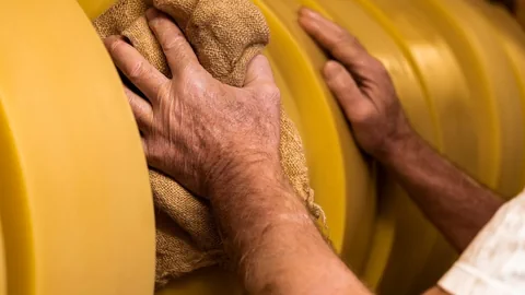 Käser reibt pflegt die Käse-Laibe