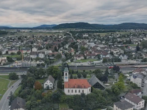 Luftaufnahme einer Stadt mit Kirche im Vordergrund und bewölktem Himmel.