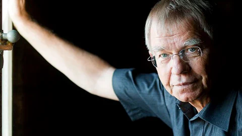 Klaus Heer lehnt sich an die Türe und schaut kritisch in die Kamera.