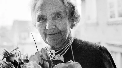 Eine ältere Dame vor einem Blumenstrauss