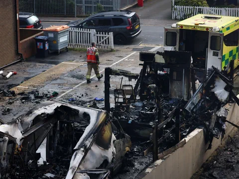 Feuerwehrmann neben ausgebrannten Fahrzeugen und Krankenwagen.