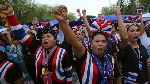 Demonstrantinnen in den thailändischen Farben recken Fäuste in die Höhe