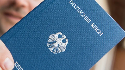 Eine Person hält einen erfundenen Reisepass mit der Aufschrift «Deutsches Reich» in der Hand.