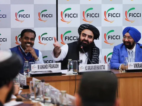 Männer am Konferenztisch mit FICCI-Logo im Hintergrund.