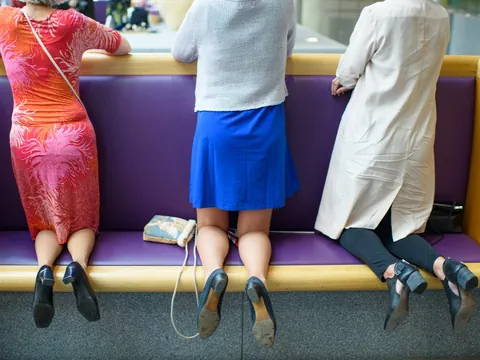 Drei Personen lehnen sich an ein Geländer mit lila Kissen.