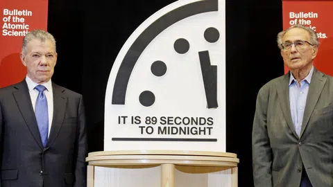 Zwei Männer stehen neben der Doomsday Clock bei 89 Sekunden bis Mitternacht.