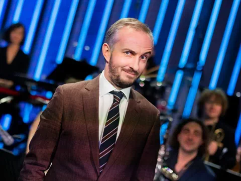 Mann im Anzug mit verschwommenem Publikum im Hintergrund.