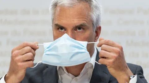 Mann hält eine blaue Gesichtsmaske vor dem Gesicht.