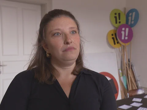 Person in einem Raum mit bunten Schildern im Hintergrund.
