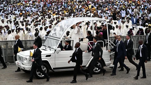 Menschenmenge umgibt ein Fahrzeug mit Sicherheitsbeamten.