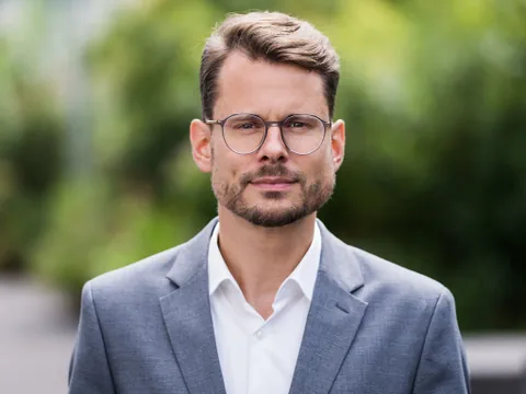 Mann mit Brille in grauem Anzug.