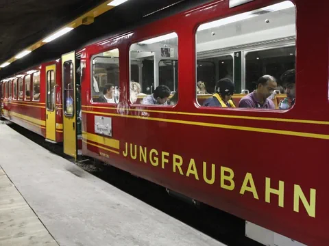 Ein beleuchteter Zug der Jungrfraubahn steht in einem Tunnel aus Fels.