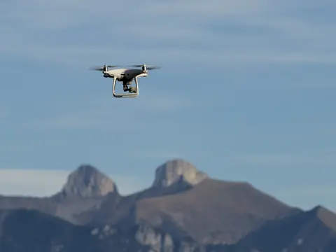 Eine Drohne fliegt vor einer Bergkulisse.