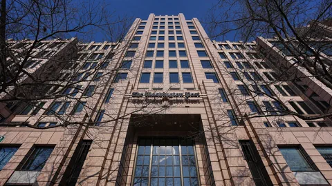 Hohe Gebäudefassade mit Bäumen im Vordergrund.