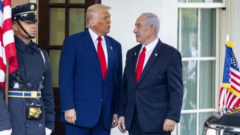 Zwei Männer in Anzügen vor Tür, US-Flagge rechts.