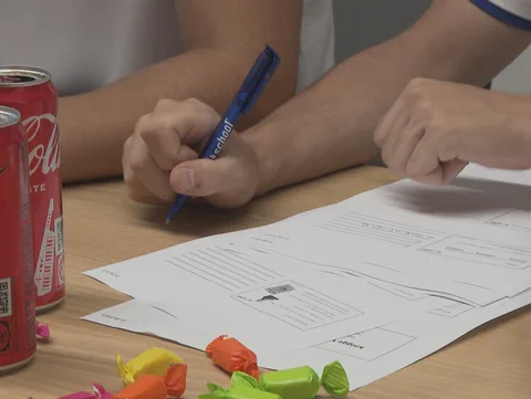 Arbeitspapaier und Hände, die einen Stift halten.