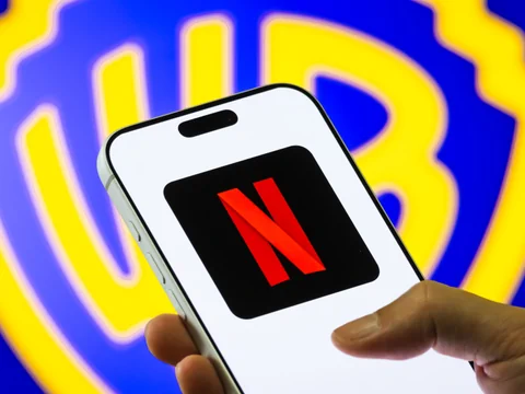 Smartphone mit Netflix-Logo vor Warner Bros. Hintergrund.