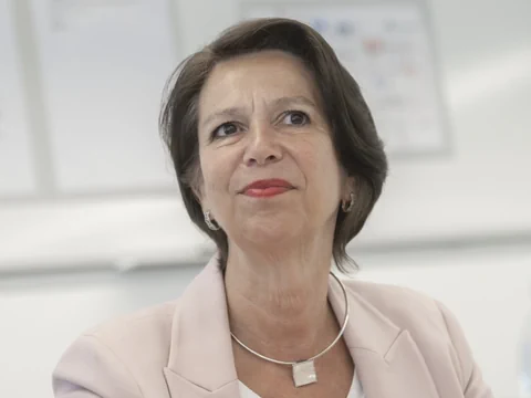 Frau mit kurzem dunkelbraunem Haar in rosa Blazer.