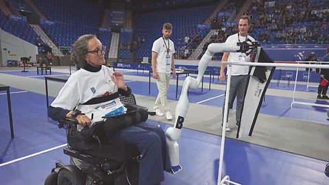 Gabi Pozzi in einer grossen Eventhalle, mithilfe des Roborterarms wird ein Tuch über eine Stange geängt.