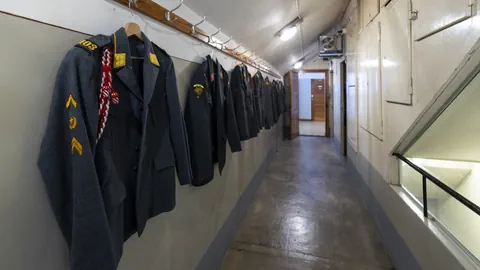 Militäruniformen an Wänden eines engen Flurs aufgehängt.