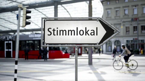 Schild mit Aufschrift 'Stimmlokal' und Richtungspfeil.