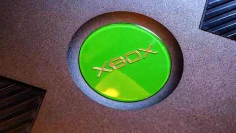 Nahaufnahme einer Xbox von Microsoft. Zu sehen das grüne Logo auf einem Gerät mit schwarzem Gehäuse.