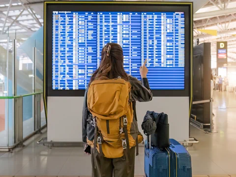 Reisende vor Abflugtafel am Flughafen.