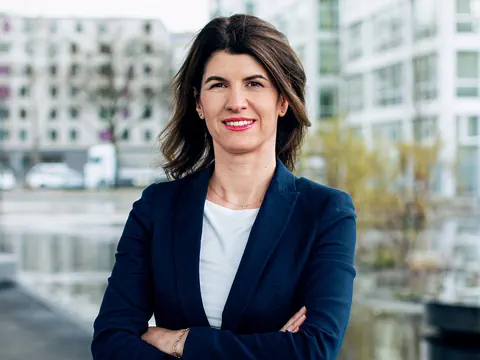 Frau in blauem Blazer vor modernem Gebäude.