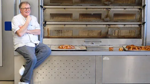 Ein Mann sitzt neben seinen Backmaschienen.