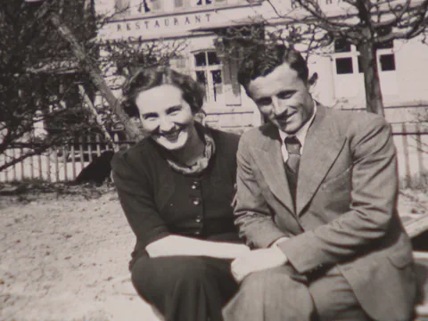 Schwarz-Weiss-Foto eines lachenden Paares vor einem Gebäude.