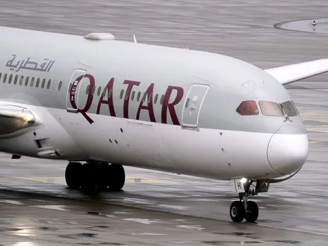 Ein graues Flugzeug der katarischen Fluggesellschaft Qatar Airways auf einem Rollfeld.