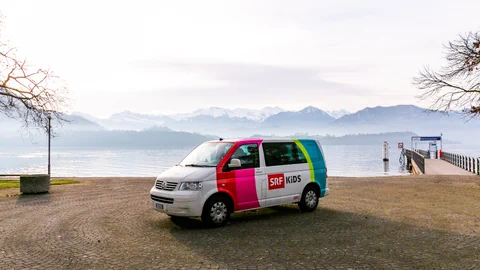 Der SRF Kids Bus vor einem See.