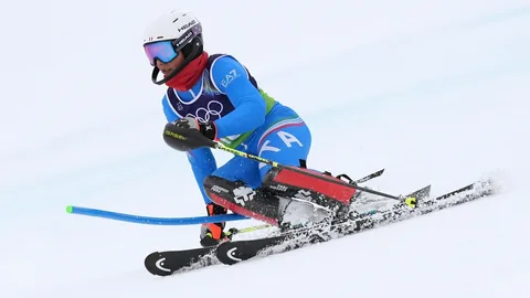 Person in blauer Skiausrüstung beim Skifahren im Schnee.