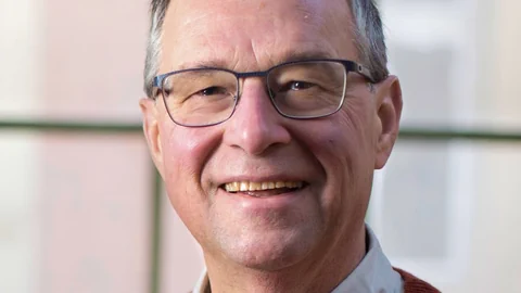 älterer Herr mit Brille lächelt. 