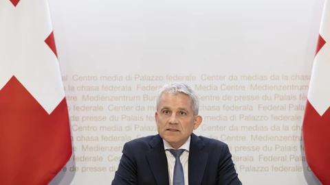 Beat Jans vor Schweizer Flaggen auf Pressekonferenz.