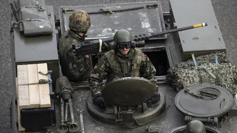 Soldaten in Tarnuniform auf einem Militärfahrzeug.