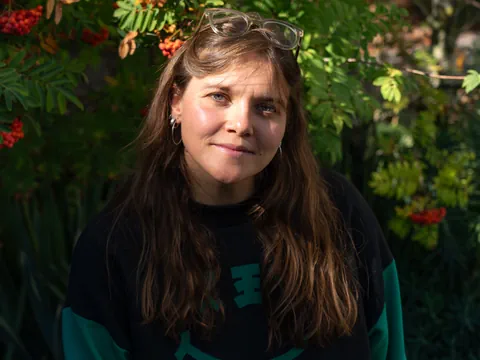Eine junge Frau steht vor einem Baum mit Früchten