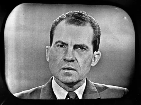 Schwarzweiss-Porträt eines Mannes im Anzug auf einem Bildschirm.