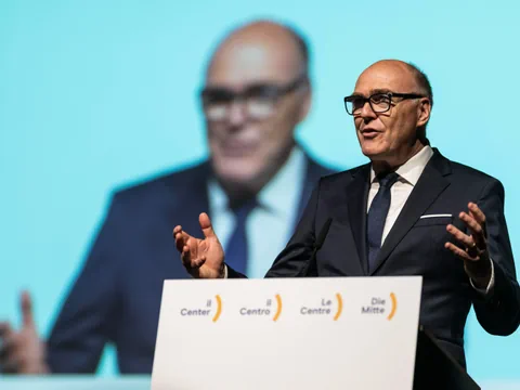 Mann auf Bühne vor einem Rednerpult und Bildschirm.