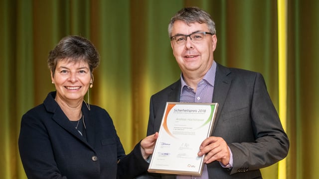 Ein Mann im Anzug zeigt eine Urkunde. Er erhält sie von bfu-Direktorin Brigitte Buhmann, die ihm die Hand schüttelt. Ein Mann im Anzug zeigt eine Urkunde. Er erhält sie von bfu-Direktorin Brigitte Buhmann, die ihm die Hand schüttelt.