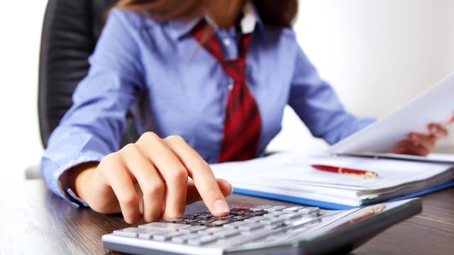 Frau im Büro mit Taschenrechner Frau im Büro mit Taschenrechner