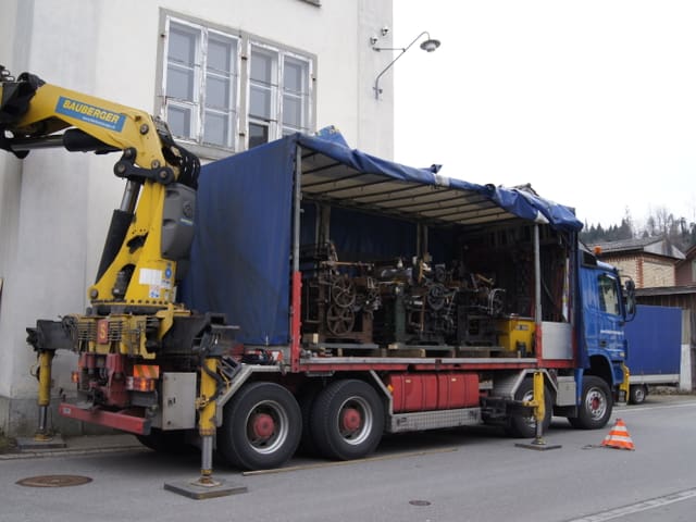 Lastwagen mit drei Webstühlen drin vor Fabrik