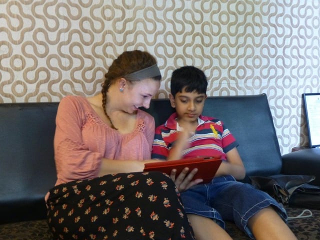Eine junge Amerikanerin zeigt einem autistischen indischen Kind etwas auf einem iPad. Eine junge Amerikanerin zeigt einem autistischen indischen Kind etwas auf einem iPad.