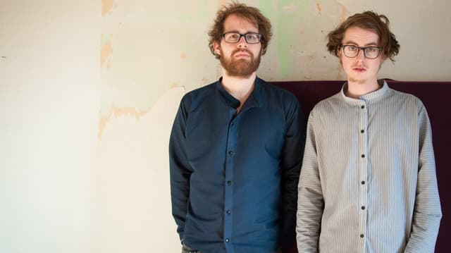 zwei bärtige und brillentragende hipster gucken desinteressiert in die kamera zwei bärtige und brillentragende hipster gucken desinteressiert in die kamera