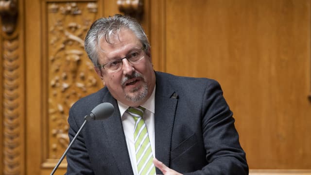 Ein Mann spricht an einem Pult in ein Mikrofon Ein Mann spricht an einem Pult in ein Mikrofon