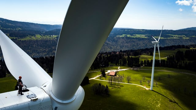 Ein Mann steht auf einer Windturbine auf dem Mont-Soleil. Ein Mann steht auf einer Windturbine auf dem Mont-Soleil.