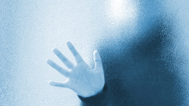 Eine Hand einer unbekannten Person an einer Fensterscheibe. Eine Hand einer unbekannten Person an einer Fensterscheibe.