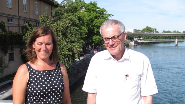 Zwei Personen stehen auf einer Brücke, dahinter ein Fluss Zwei Personen stehen auf einer Brücke, dahinter ein Fluss