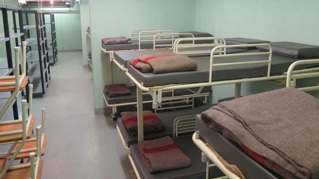Bunkermässiges Zimmer mit Doppelstockbetten, auf denen Armeewolldecken liegen. Bunkermässiges Zimmer mit Doppelstockbetten, auf denen Armeewolldecken liegen.