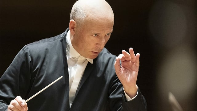 Mann Mittleren Alters dirigiert mit Dirigentenstab in der Hand Mann Mittleren Alters dirigiert mit Dirigentenstab in der Hand